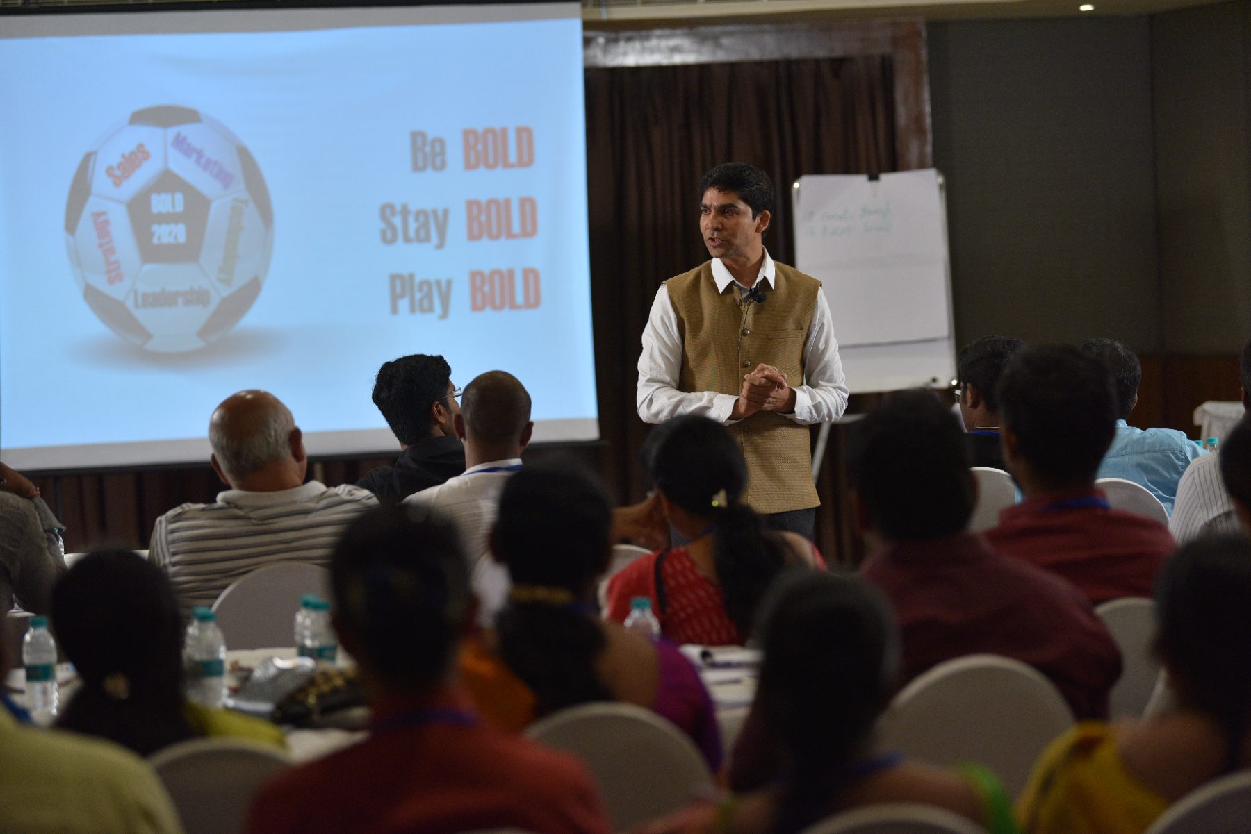 Venu Bhagavan on stage in front of a full room
